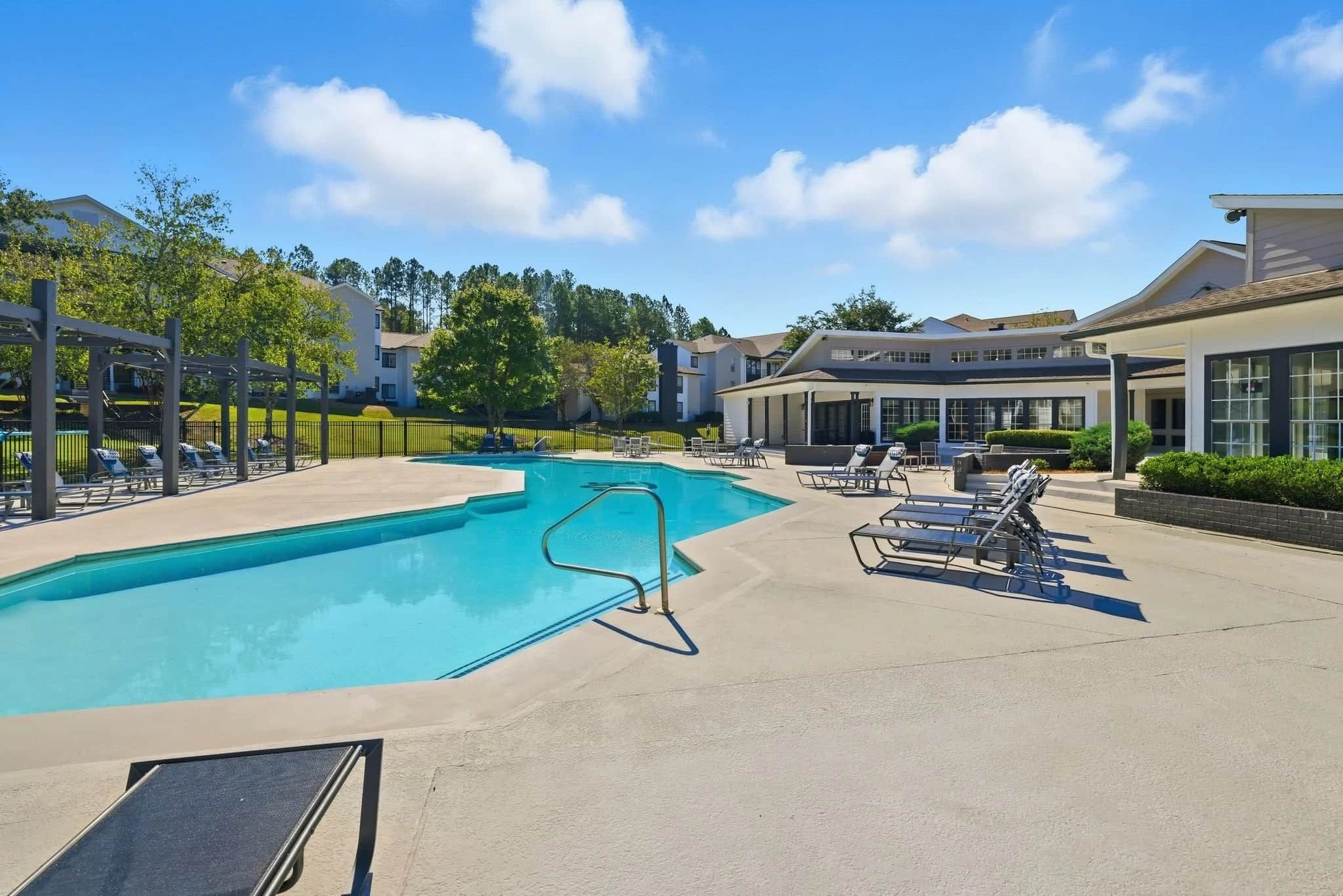 A swimming pool with lounge chairs and a covered patio area.