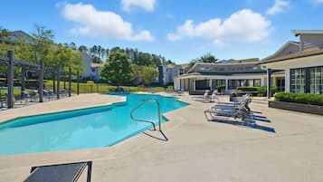 A swimming pool with lounge chairs and a covered patio area.