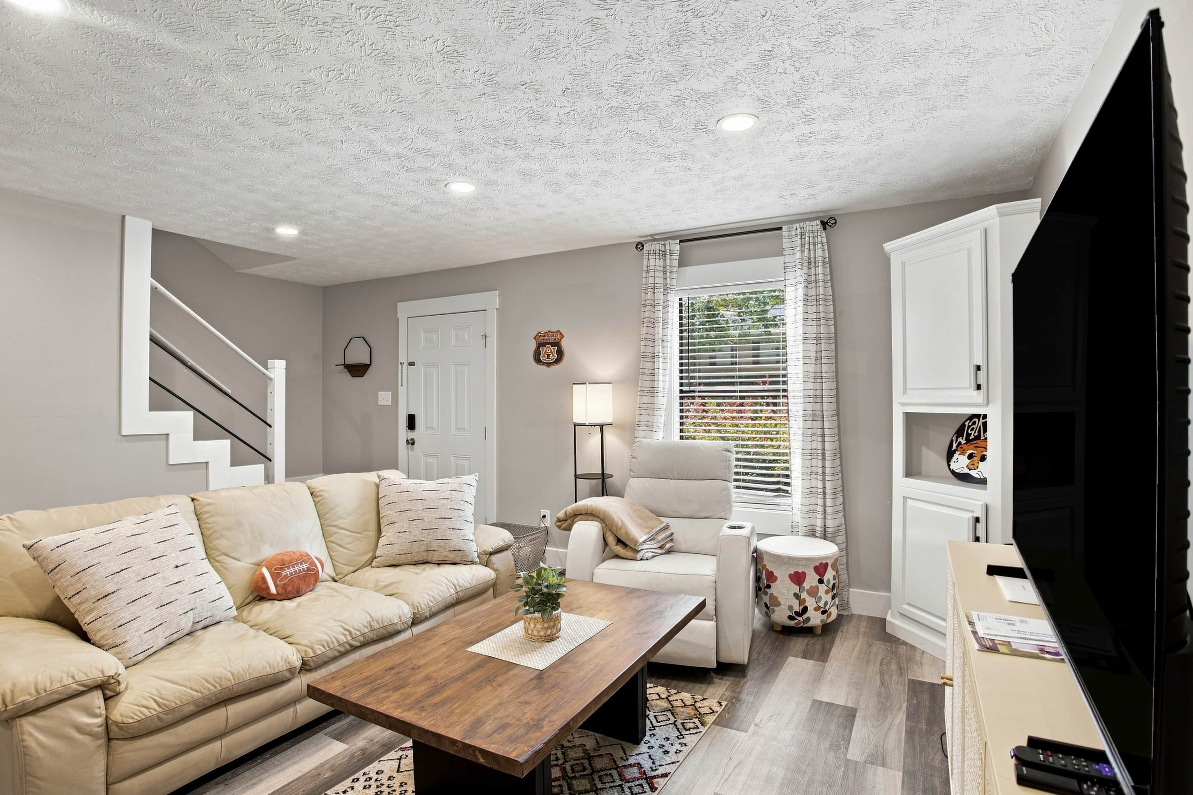 A living room with a sofa, a coffee table, a TV, and a staircase.