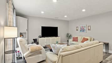 A living room with a flat-screen TV, two sofas, a coffee table, and a lamp.