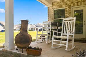 A patio area with a large vase, two rocking chairs, and a grill. - The Loveliest Stay in Auburn (Auburn)