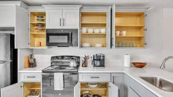 A kitchen with white cabinets, a stove, a microwave, and a coffee maker.