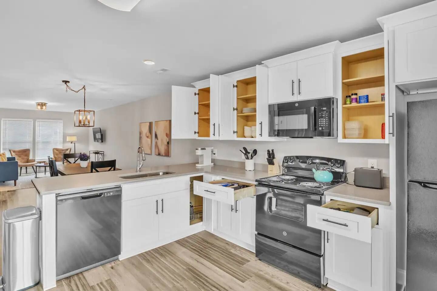Una cocina moderna con armarios blancos, electrodomésticos de acero inoxidable y piso de madera.