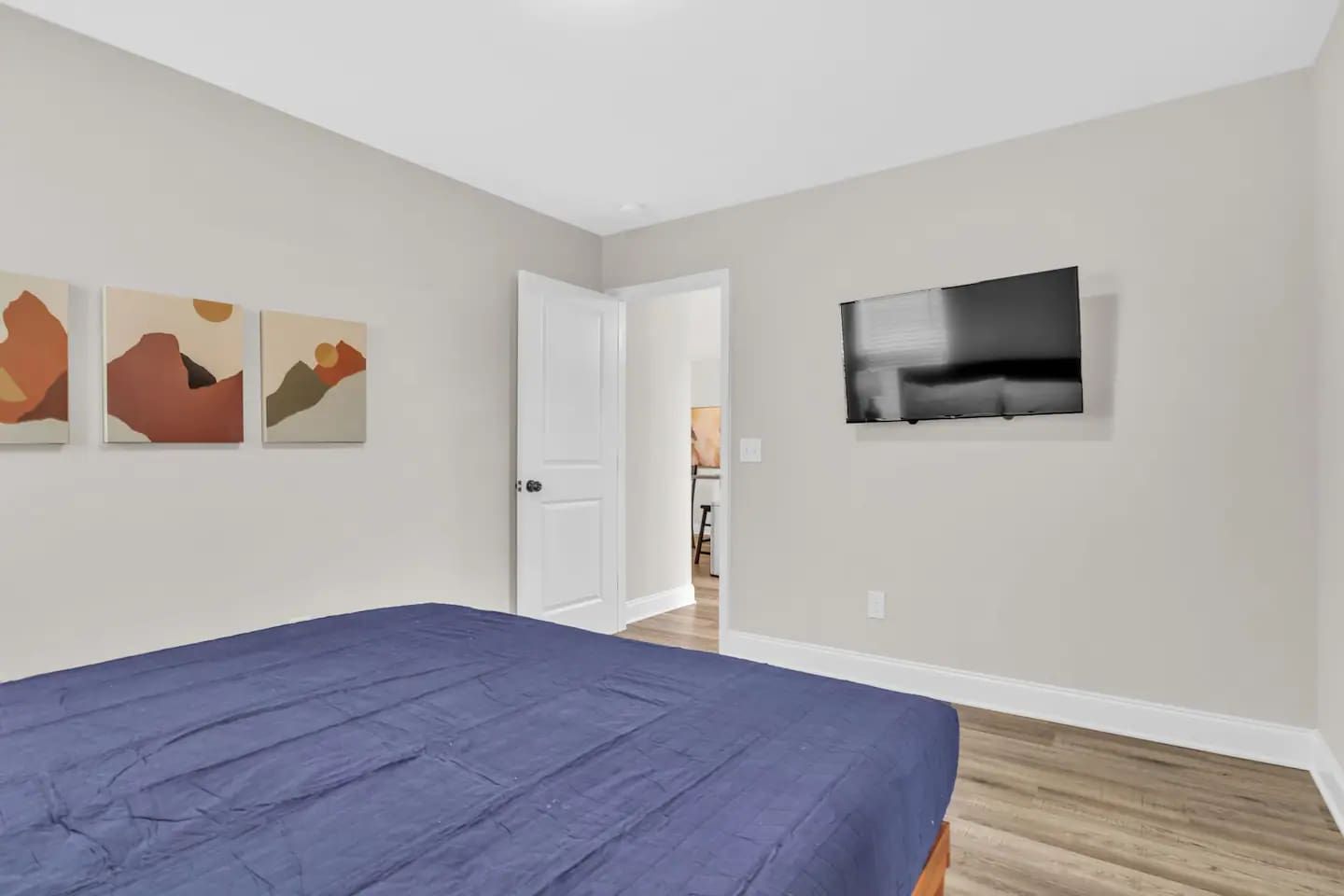 Ein Schlafzimmer mit einem Bett, einer Tür und einem Fernseher an der Wand.