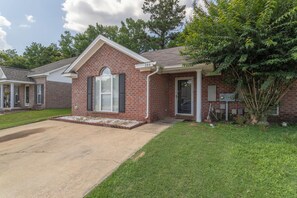 A single-story brick house with a front entrance, a small porch, and a well-maintained lawn.
