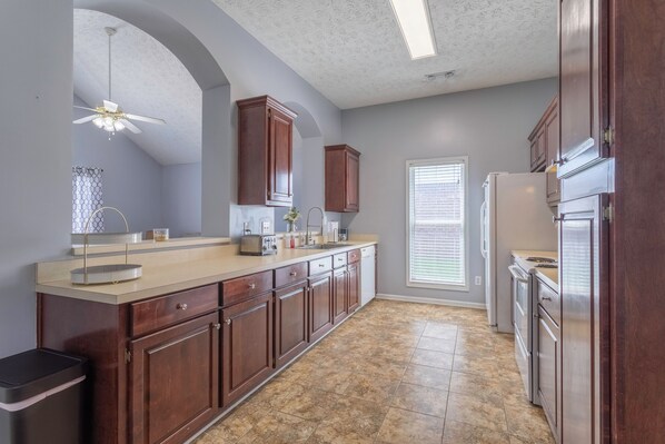 A kitchen with a central island, wooden cabinets, a built-in oven, and a window with blinds.