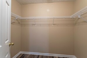 A room with a white door, beige walls, and a metal wire shelf unit.