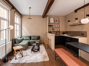A compact living space with a kitchenette, a sofa, a coffee table, and a bench. - Le Sablon Hideaway Charming House in the Heart of Brussels (Brussels)