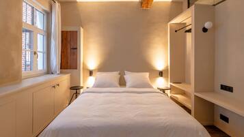A modern bedroom with a large bed, bedside tables, a wardrobe, and a window with curtains.