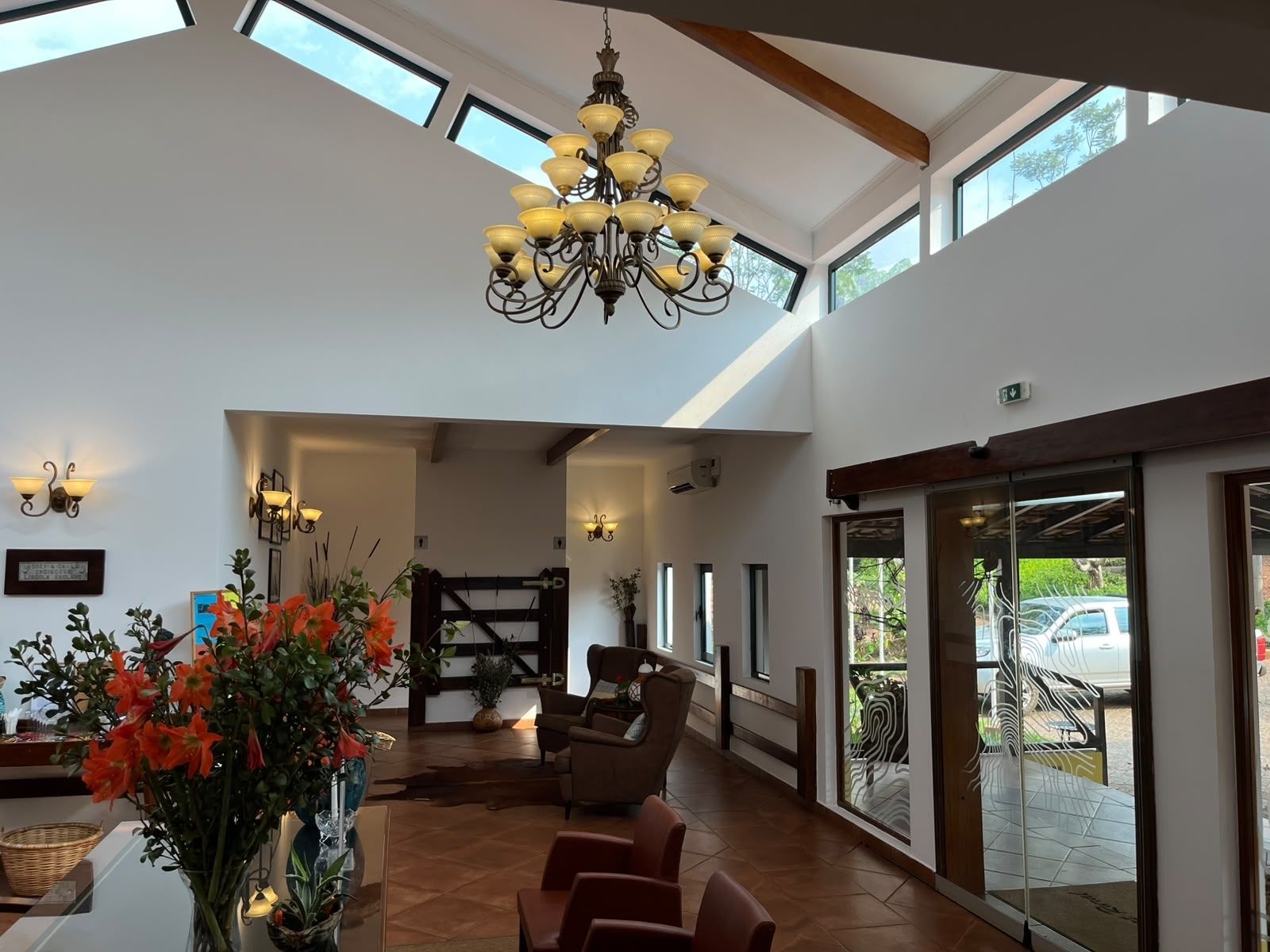 A spacious lobby with a high ceiling, a chandelier, seating area, and large windows.