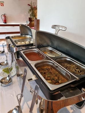 A buffet setup with various food items and serving utensils.