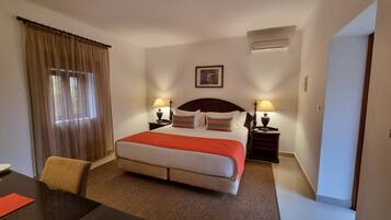 A hotel room with a bed, two bedside tables, a desk, and a chair.
