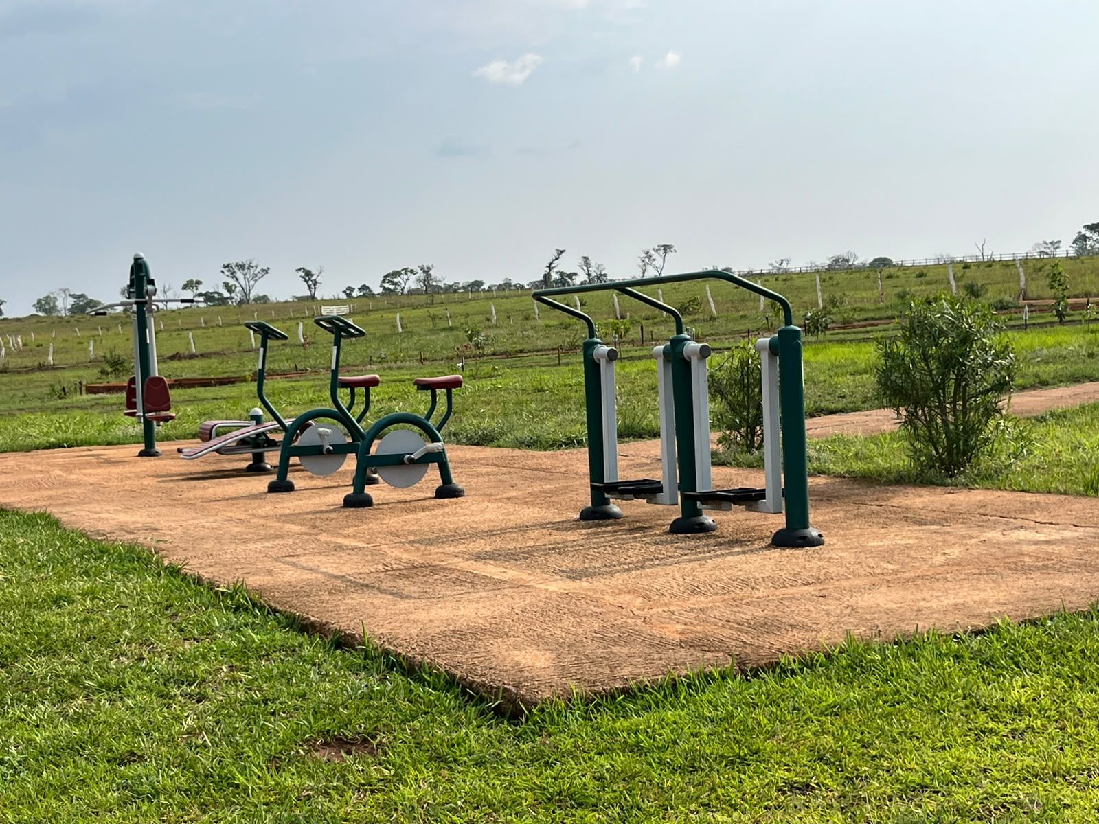 Outdoor exercise equipment in a park with a dirt path and grass.