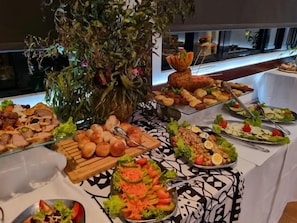 A buffet table with various food items and a decorative plant.