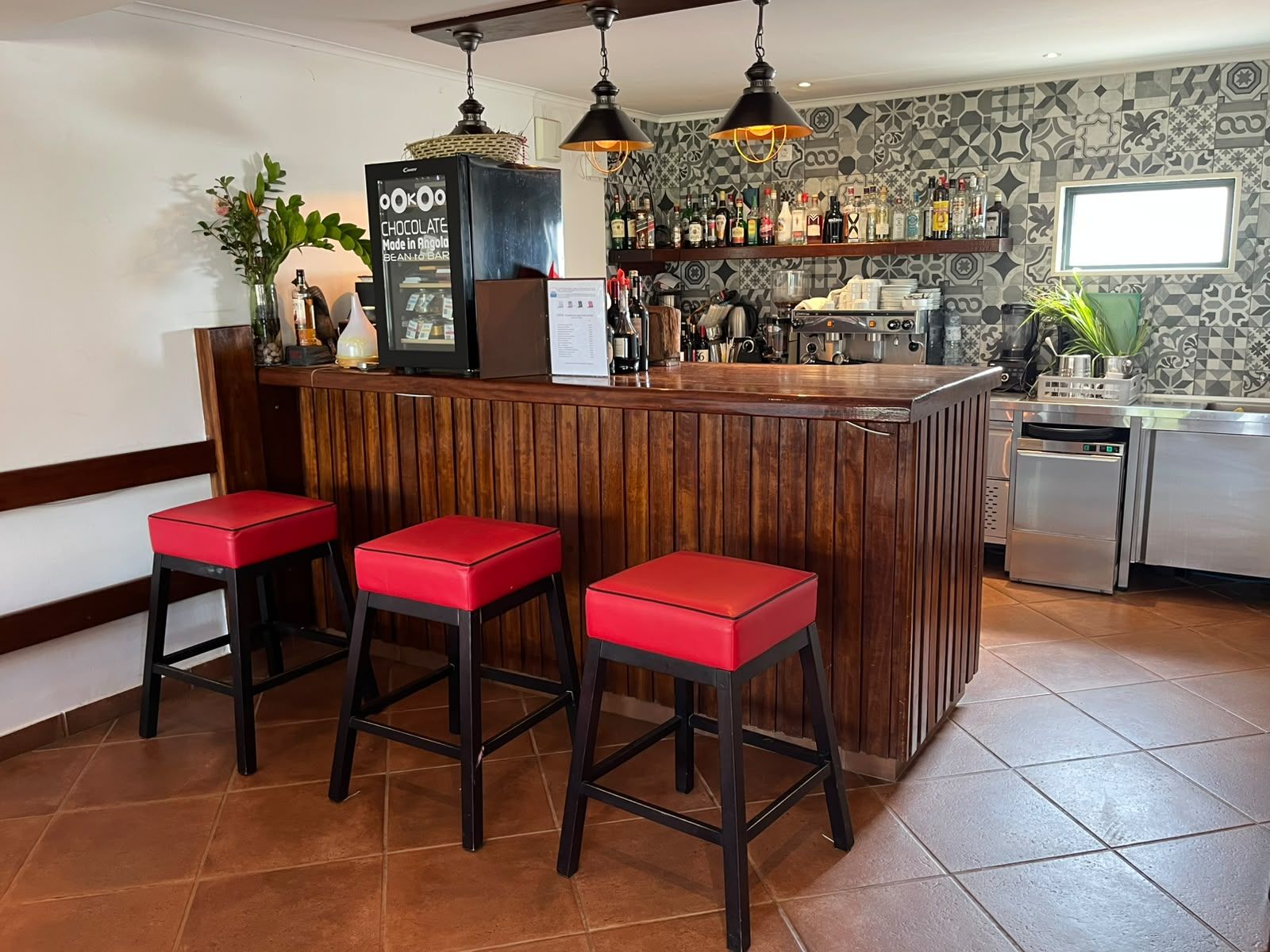 Un espace bar avec des tabourets, un réfrigérateur et une variété de bouteilles.