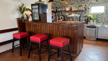 A bar area with stools, a refrigerator, and a variety of bottles.