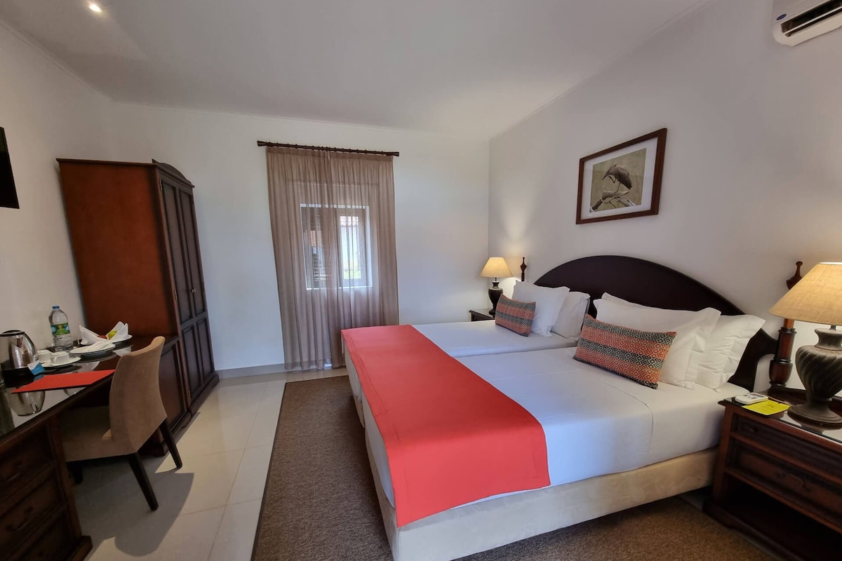 Una camera d'albergo con un letto, comodini, una scrivania e un armadio.