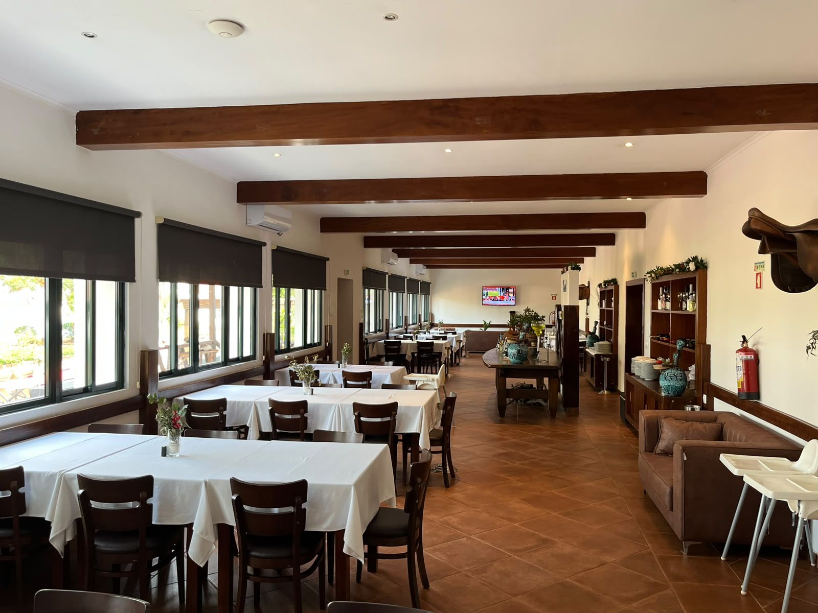 A restaurant with multiple tables and chairs, a television in the background, and a fireplace.