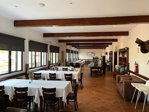 A restaurant with multiple tables and chairs, a television in the background, and a fireplace.