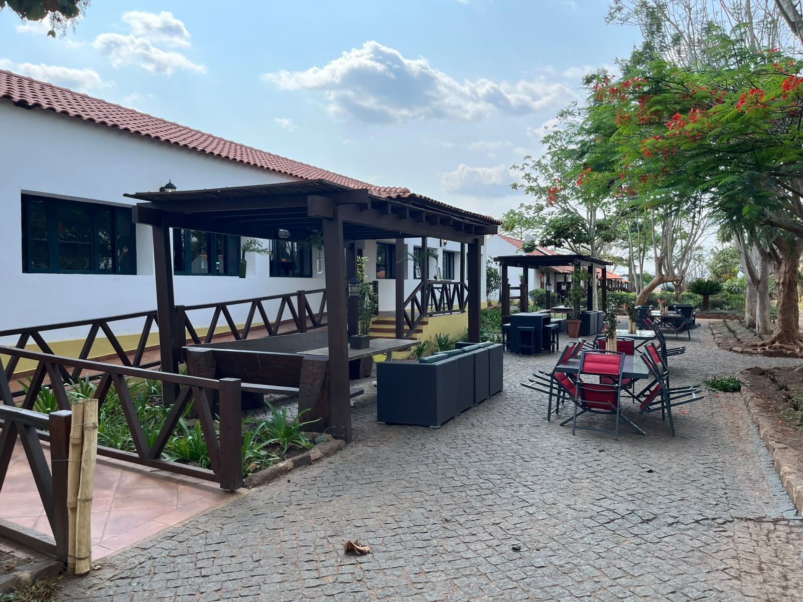 An outdoor patio area with seating arrangements, a covered seating area, and a building with windows.