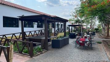 An outdoor patio area with seating arrangements, a covered seating area, and a building with windows.