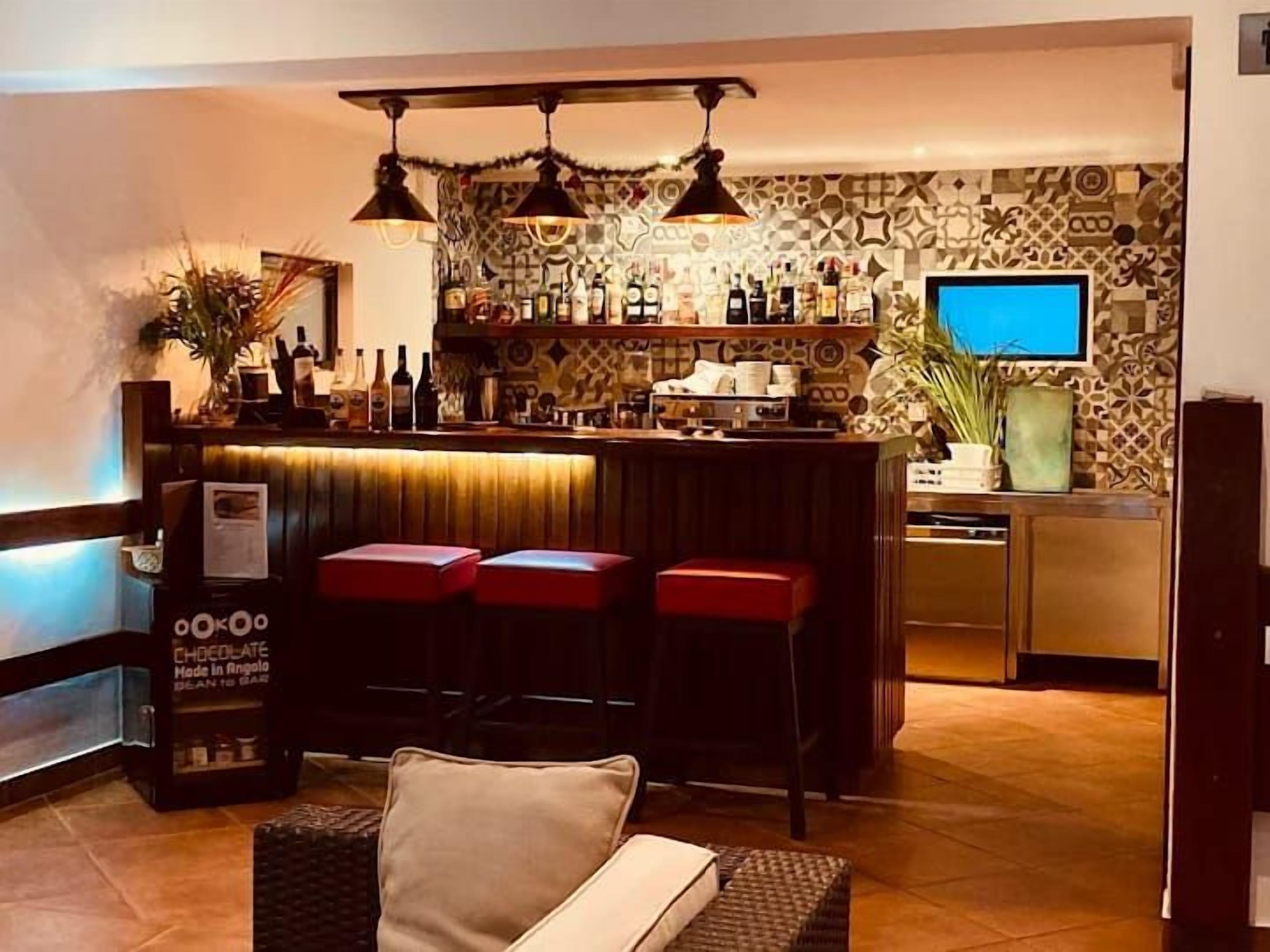 Un espace bar avec des tabourets, un téléviseur et un mur décoré de motifs.