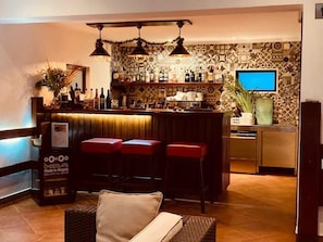 A bar area with stools, a television, and a patterned wall.