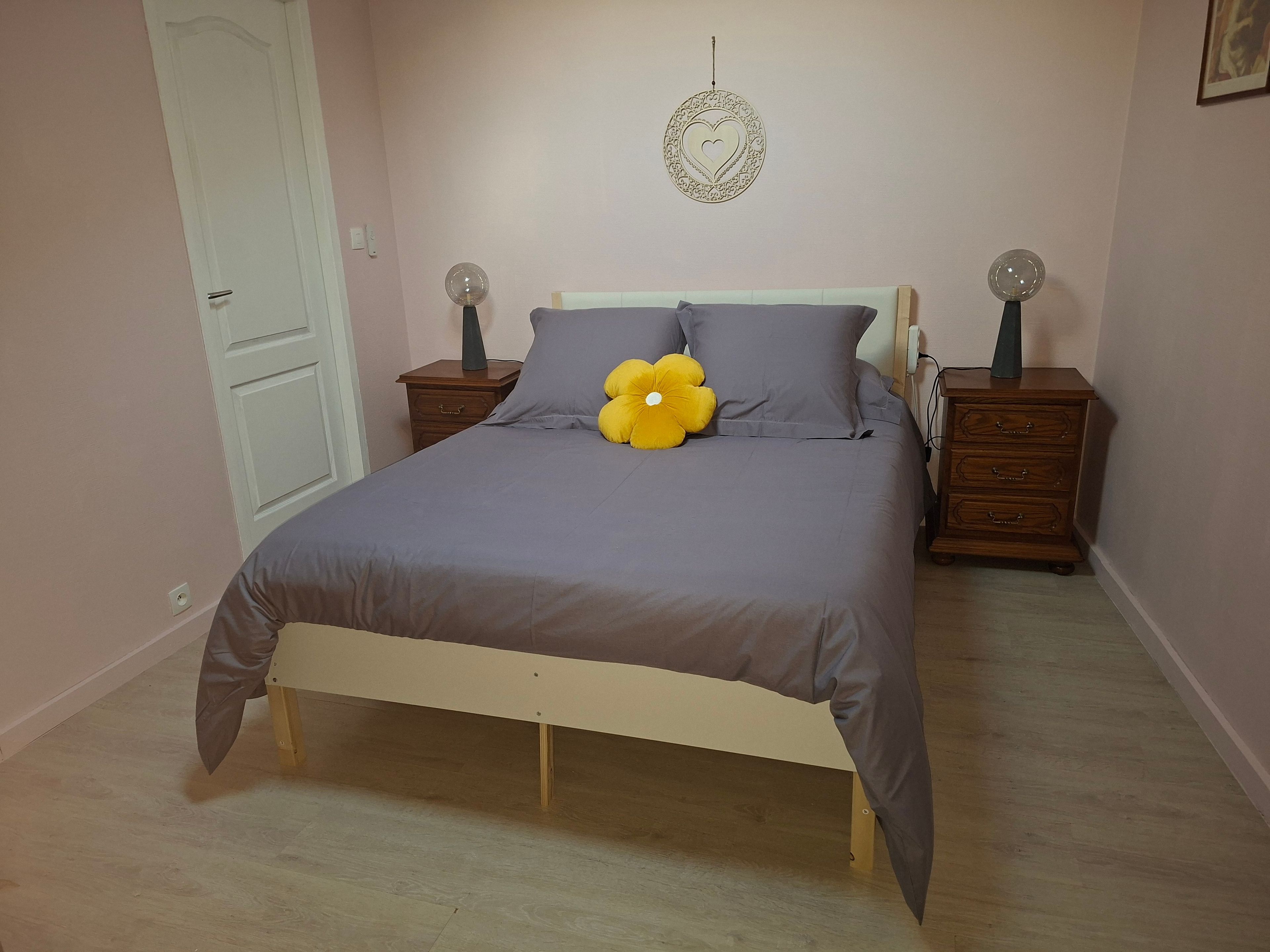 Een slaapkamer met een bed, twee nachtkastjes, een wanddecoratie en een deur.