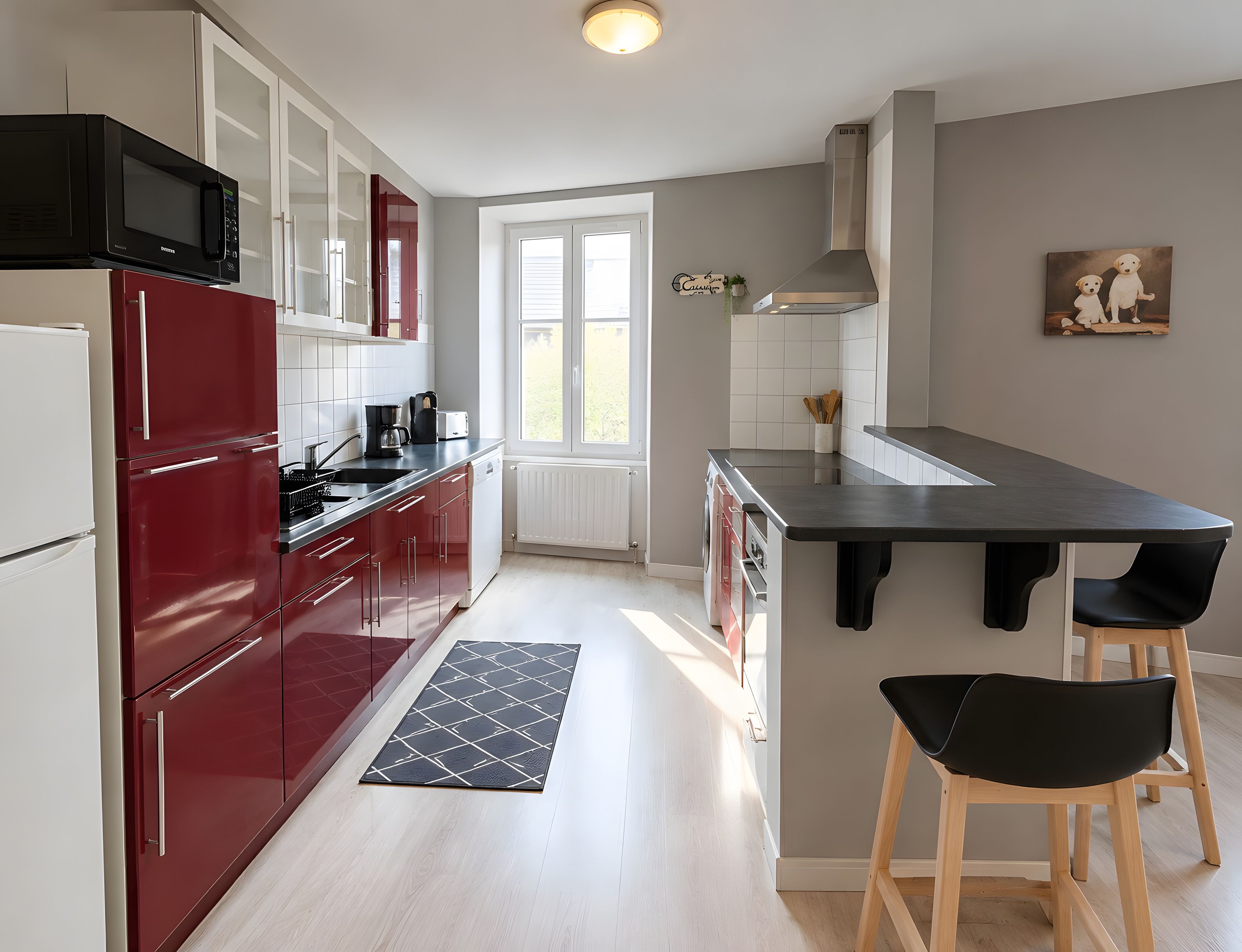 A modern kitchen with a built-in microwave, red cabinets, a black countertop, and a window with a view.