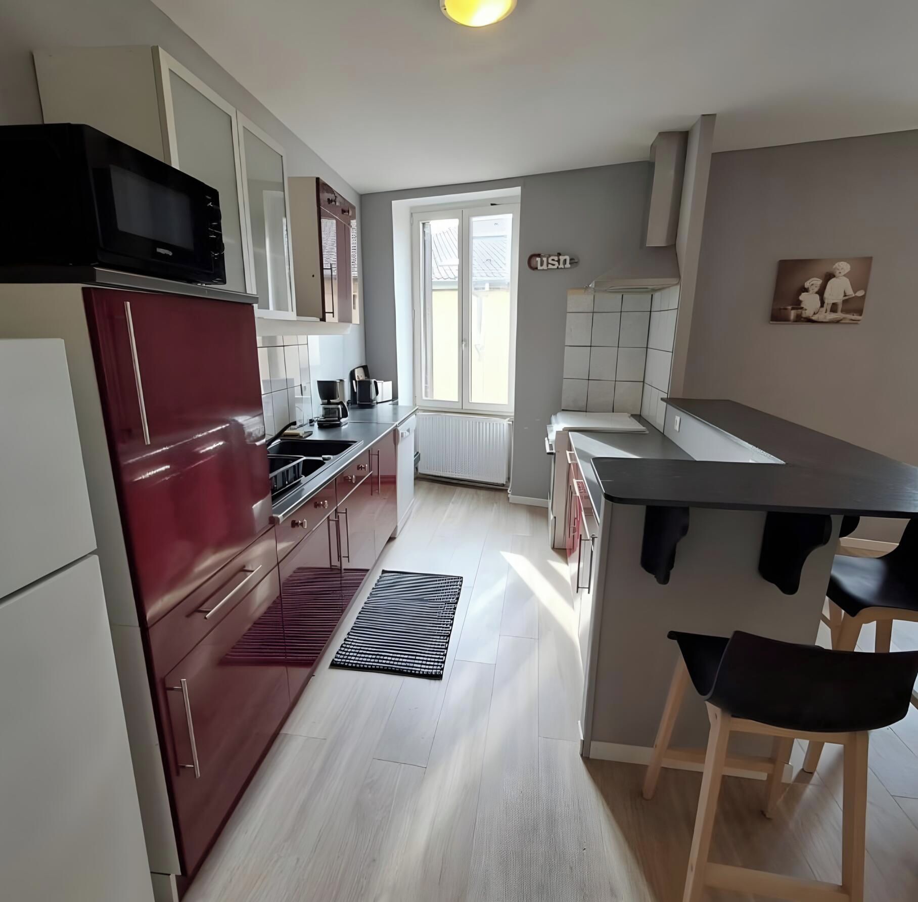 A modern kitchen with a refrigerator, stove, and sink. There is a window with a view of the outside.