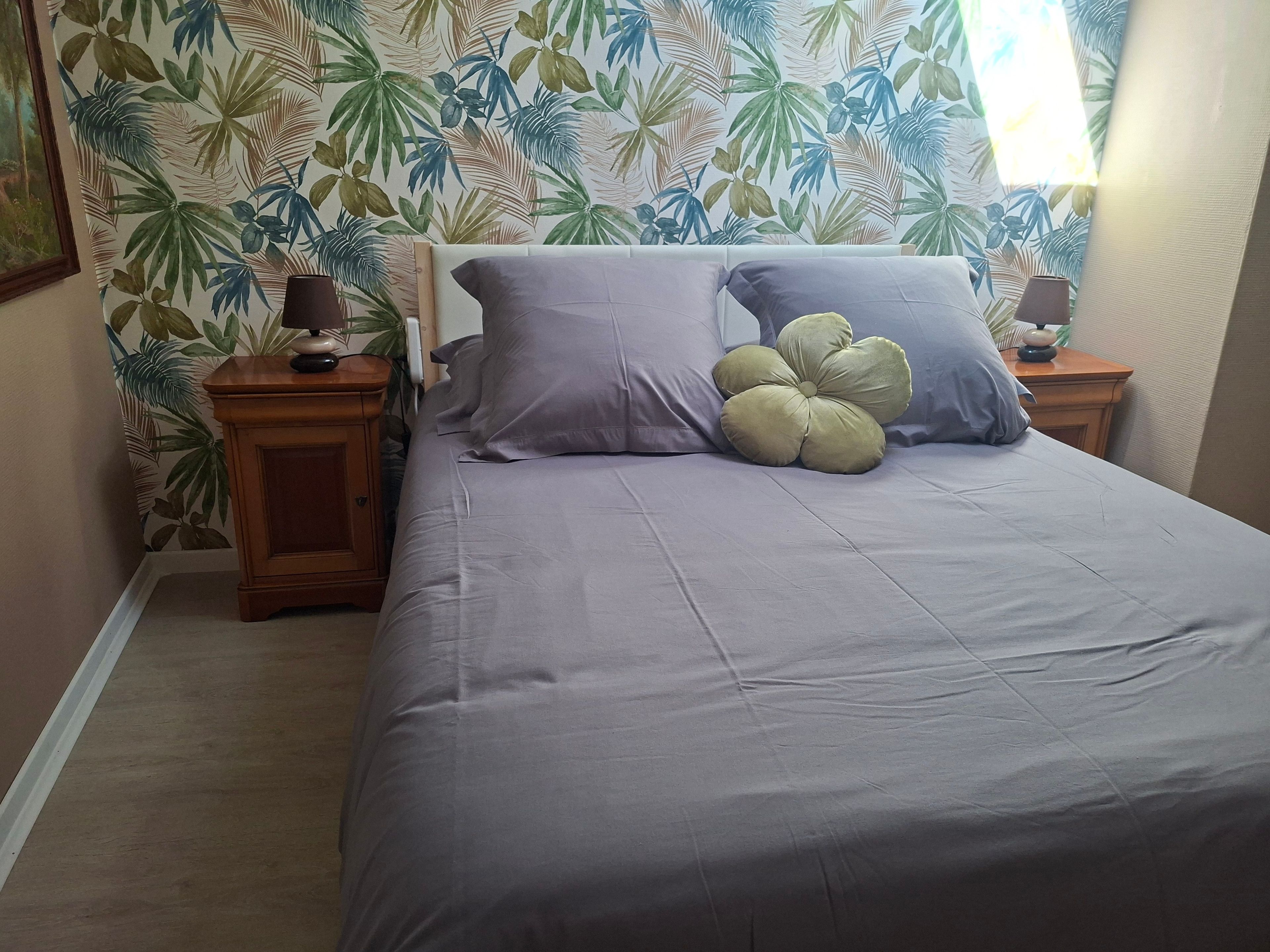 Une chambre à coucher avec un lit, deux tables de chevet, une lampe et un papier peint à motifs floraux.