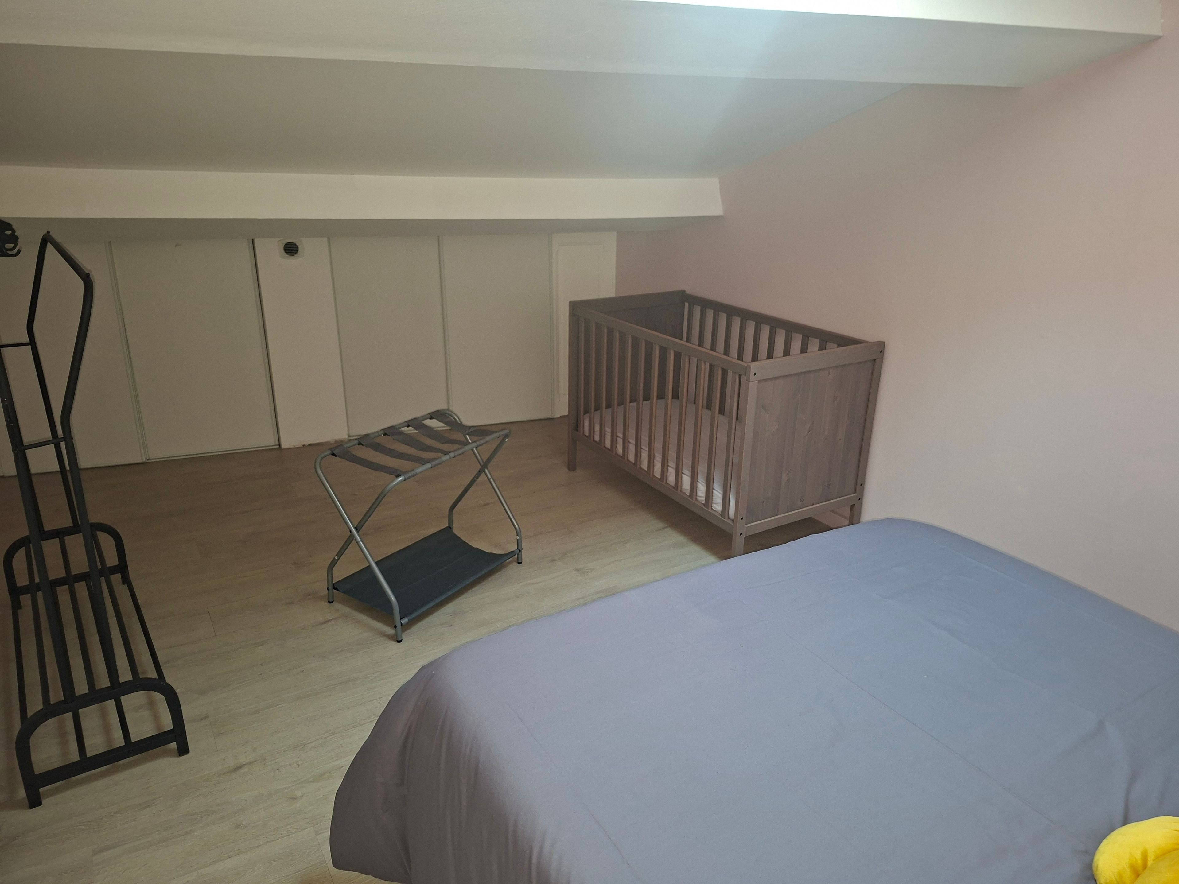 Quarto com berço, prateleira de metal e cama.