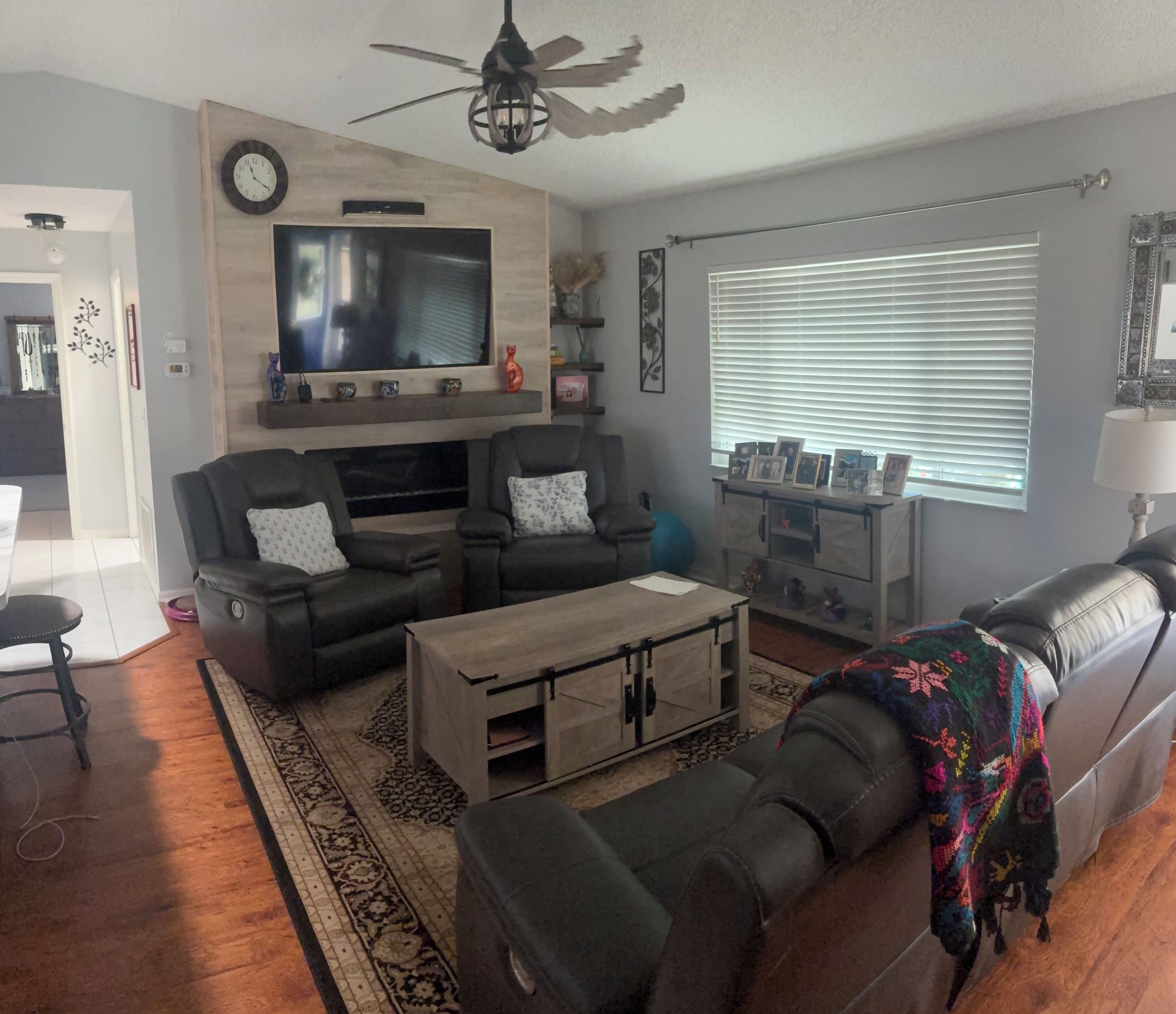 A living room with a television, sofas, a coffee table, and a patterned rug.