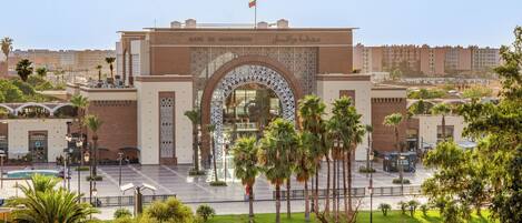 A large archway with intricate patterns, leading to a building with a flag on top.