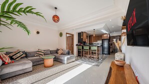 Ein modernes Wohnzimmer mit Sofa, Couchtisch und einer Küche im Hintergrund.