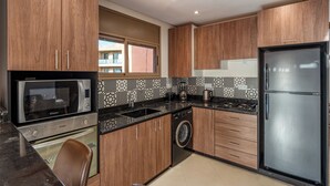 Eine moderne Küche mit Holdekor, einer integrierten Mikrowelle, einem Spülbecken, einem Herd und einem Kühlschrank.