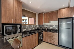 Una cocina moderna con armarios de madera, microondas integrado, un lavamanos, estufa y refrigerador.