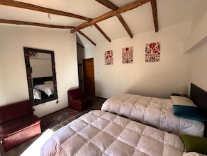 Une chambre avec deux lits, un canapé rouge, un miroir et des œuvres d’art décoratives au mur.