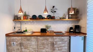 A kitchen with wooden cabinets, a sink, a coffee maker, and pendant lights.