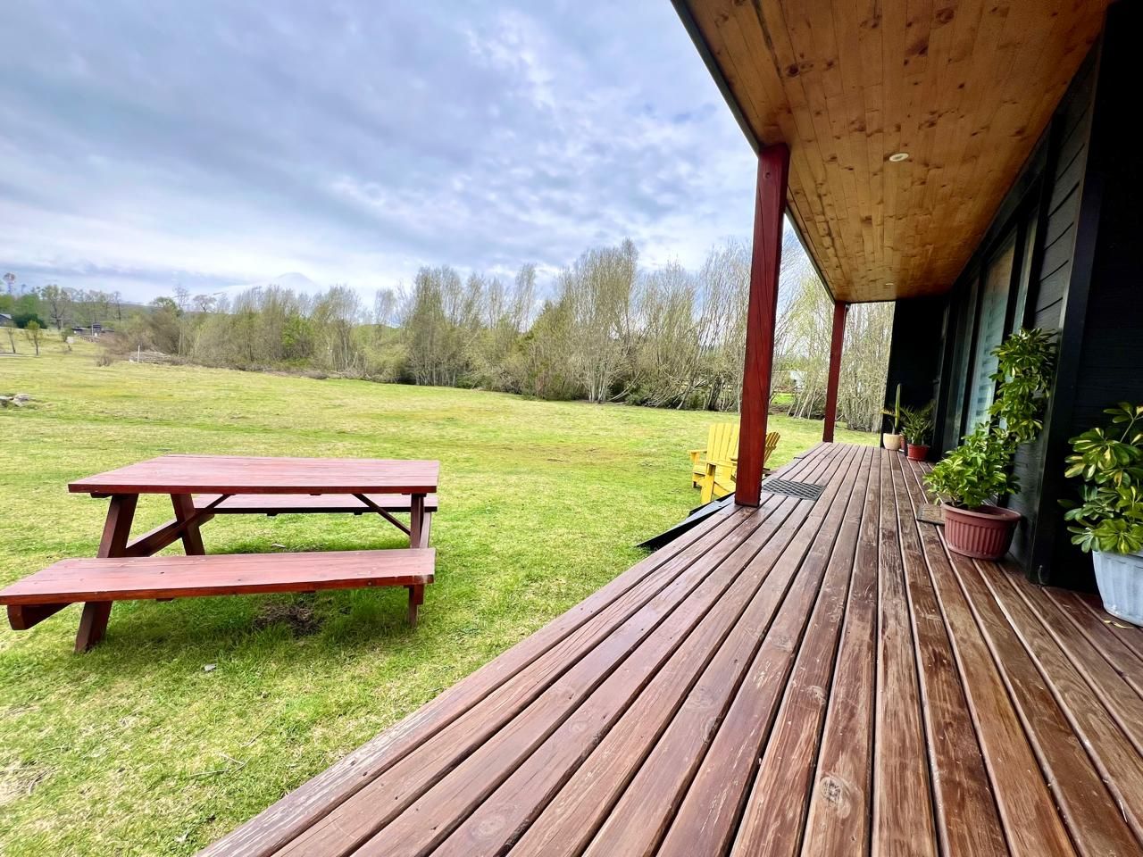 A wooden deck with a picnic table and potted plants.