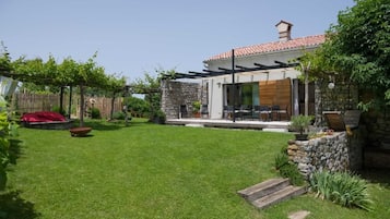 Una casa moderna con fachada de piedra, un porche cubierto y un césped cuidado.
