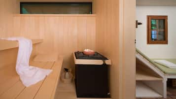 Una sala de sauna con un banco de madera, un calentador pequeño y una ventana.