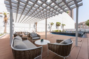 A covered outdoor seating area with wicker furniture and a pool. - Stayshort - Spacious 1 Bedroom Apartment in JVT for up to 4 Guests (Dubai)