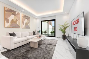 A modern living room with a sofa, coffee table, and artwork on the wall. - Stayshort - Spacious 1 Bedroom Apartment in JVT for up to 4 Guests (Dubai)