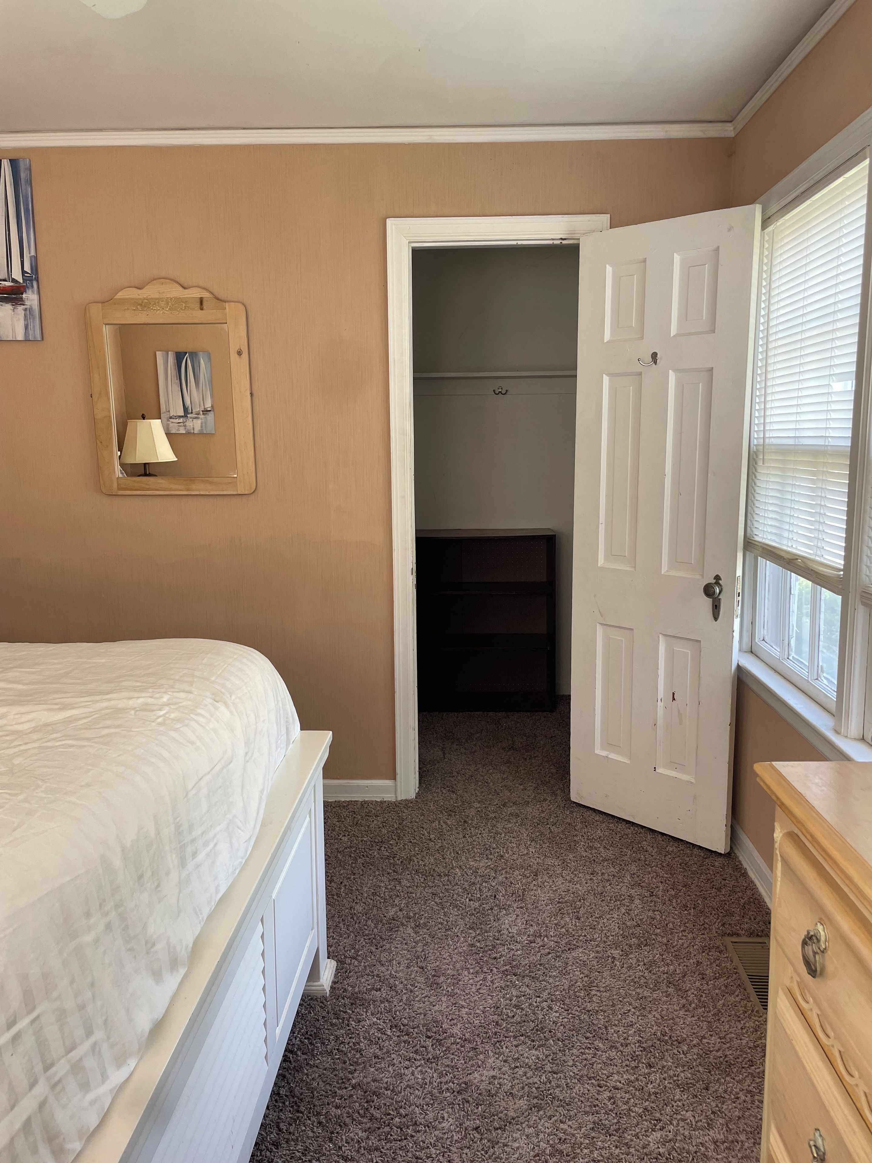 A bedroom with a bed, a dresser, a mirror, and a door leading to a closet.