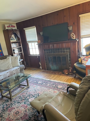 A living room with a fireplace, a sofa, a coffee table, and a patterned rug.