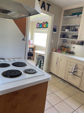 A kitchen with a stove, cabinets, and a window.
