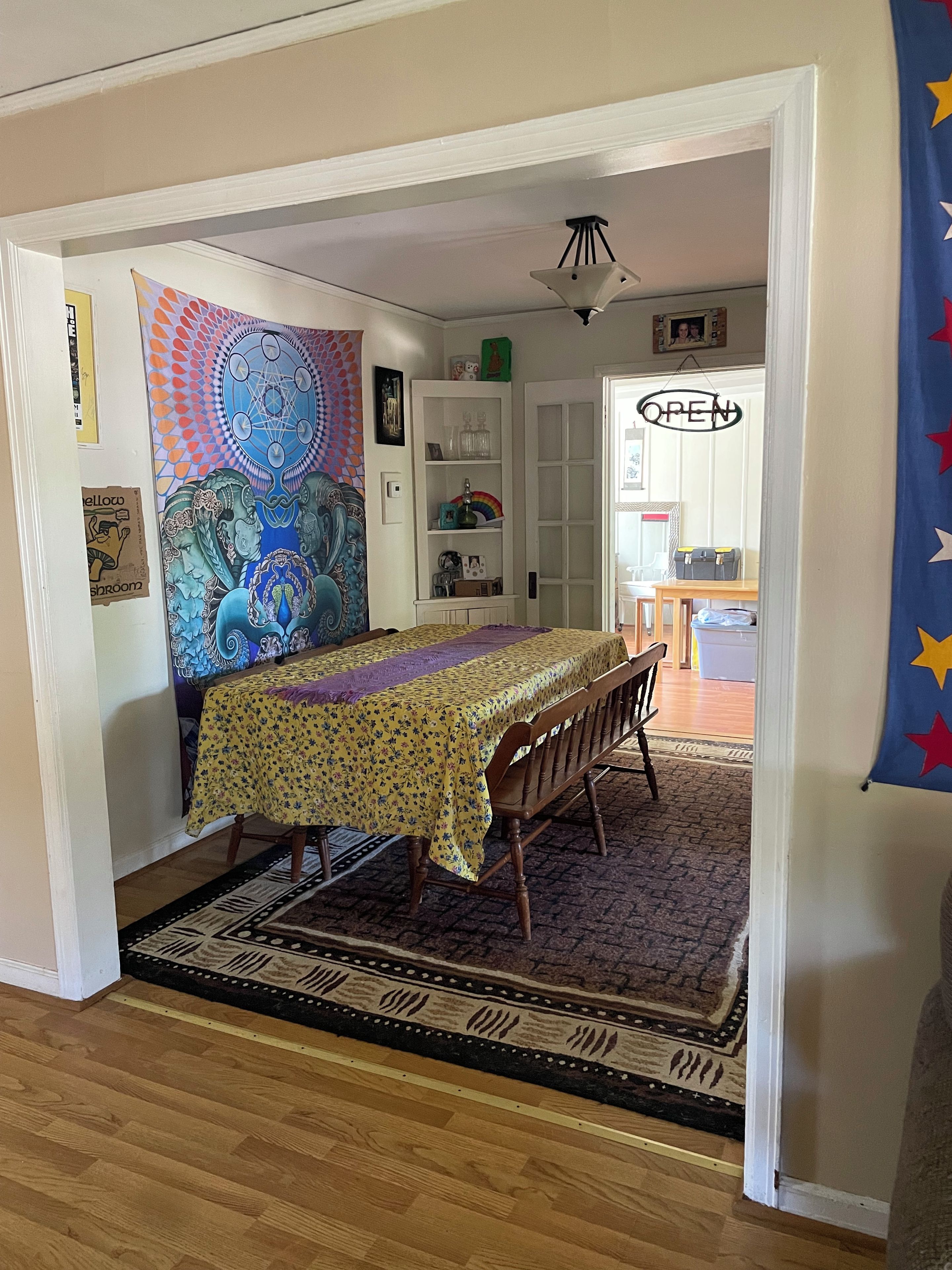 A dining area with a table set for two, a patterned rug, and a door leading to another room.