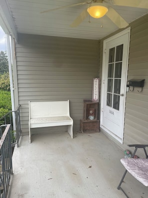 A porch with a white bench, a door labeled '1404', and a small shelf with a vintage radio.