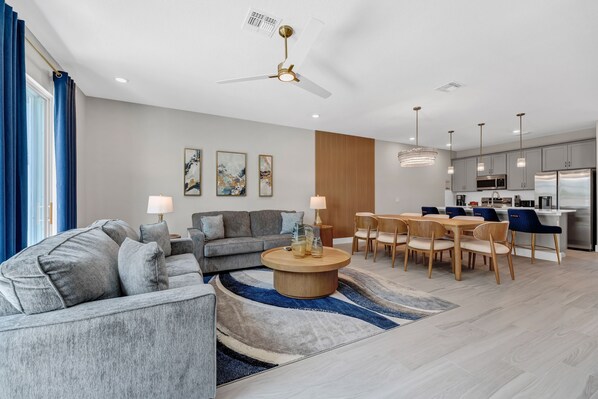 A modern living room with a sofa set, a coffee table, and a dining area with chairs and a table.